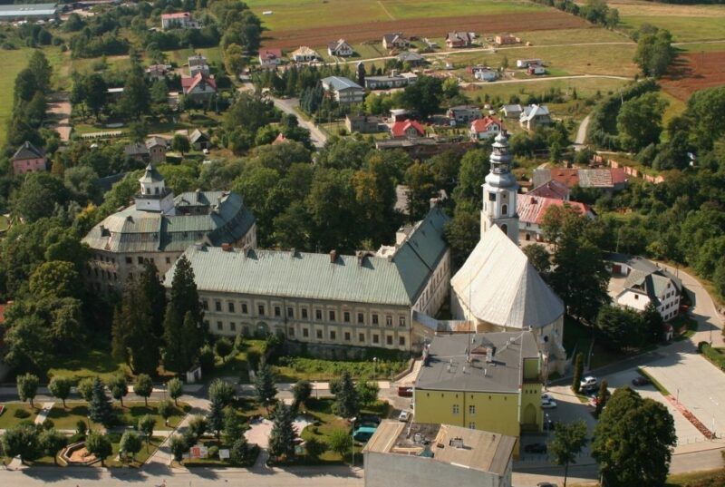 Widok na zamek z lotu ptaka, widoczne drzewa, polany oraz domki.