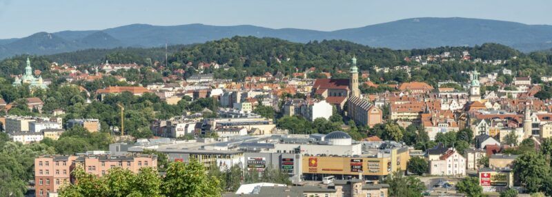 Widok z lotu ptaka na miasto, lasy oraz góry.