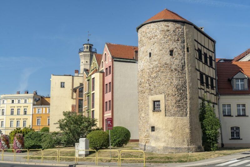 Widok na budynki, kilka kolorowych budynków oraz półokrągła ceglana budowla.