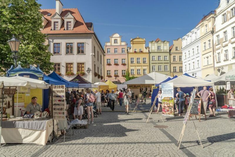 Kolorowe domy na rynku, na chodniku porozkładane namioty.
