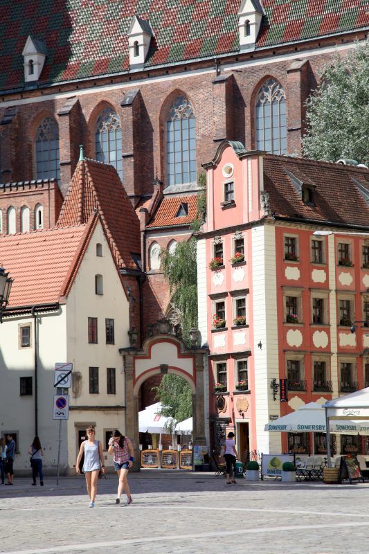 Niewielkie pastelowe budynki połączone bramą znajdujące się na wrocławskim rynku.