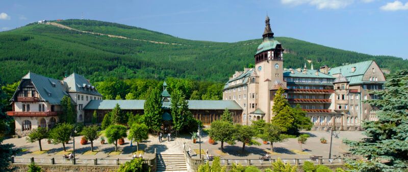 Widok na masywny budynek uzdrowiska z górą w tle