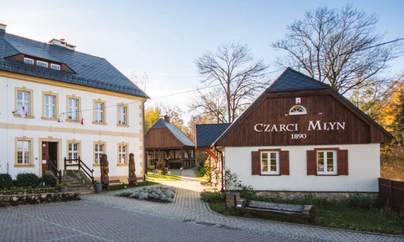 Widok na niewielką, odnowioną chatę sudecką z napisem Czarci Młyn