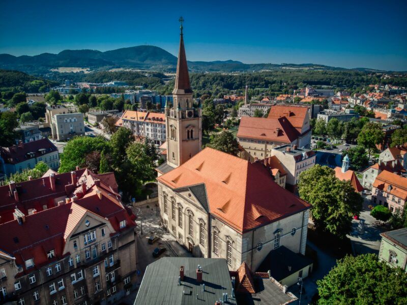 Zdjęcie z lotu ptaka na miasto z kościołem widocznym w centrum kadru i górami w tle