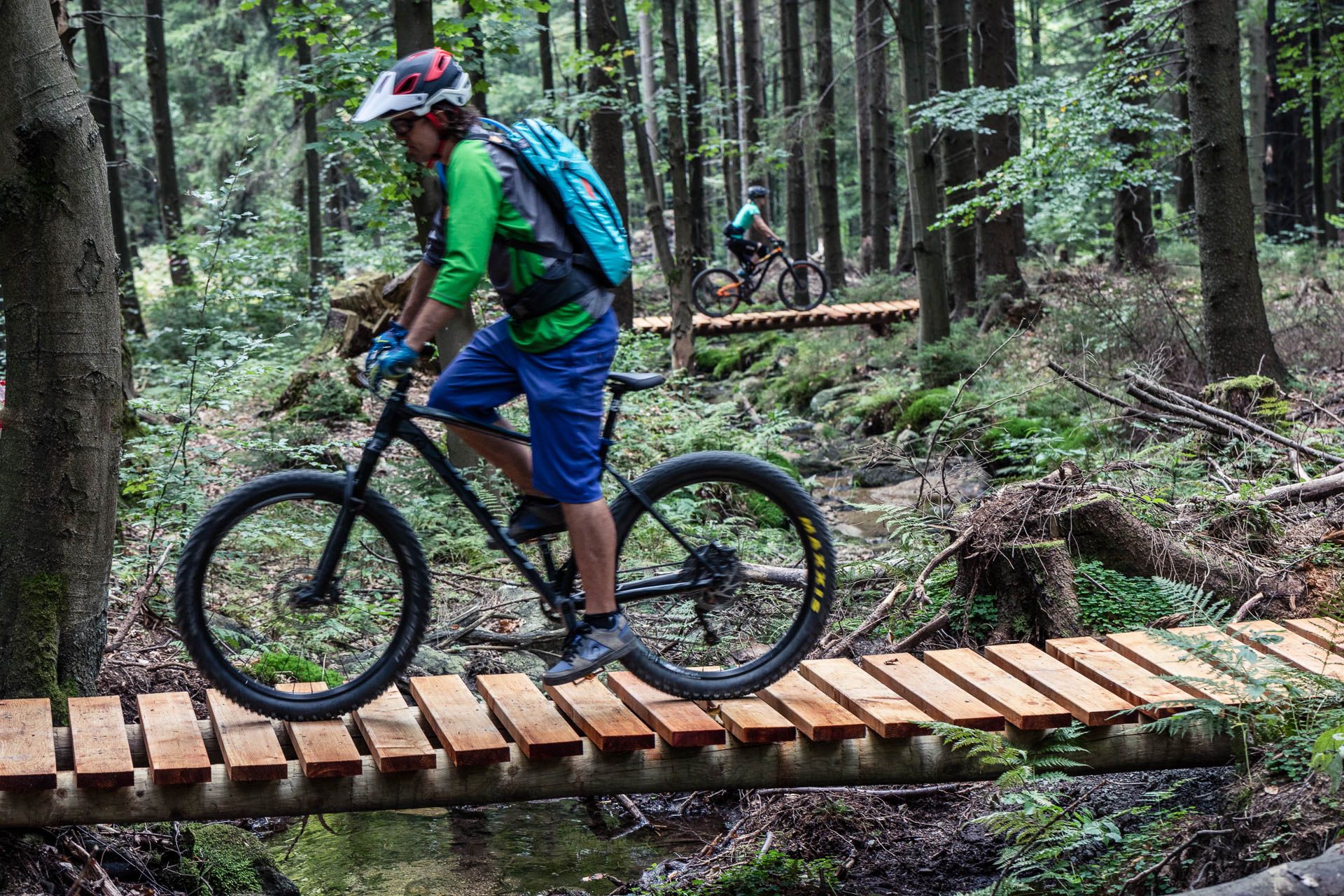 Rowerzyści przejeżdzają przez drewniane pomosty