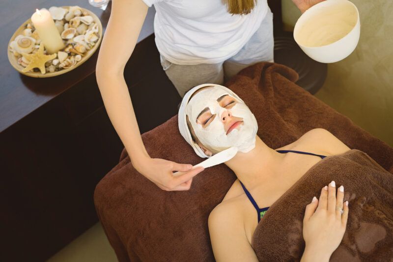 Kobieta leżąca podczas zabiegu spa z białym kremem na twarzy