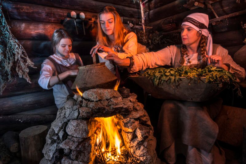 Zdjęcie grupy kobiet w średniowiecznych strojach podczas gotowania na ogniu