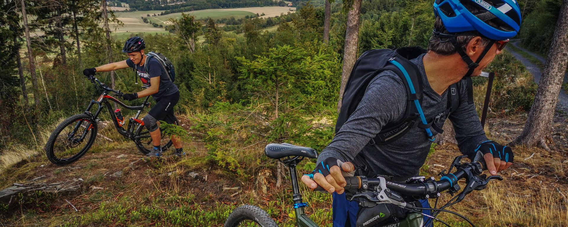 Zdjęcie dwóch rowerzystów pchających rowery pod górę