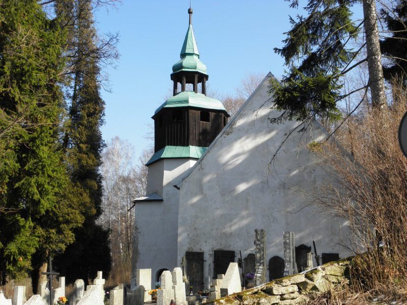 Mały zabytkowy biały kościół położony na cmentarzu