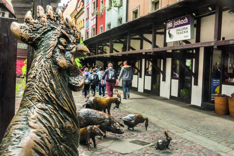 Zdjęcie zabytkowej, odtworzonej uliczki z drewnianymi podcieniami i małymi galeriami sztuki