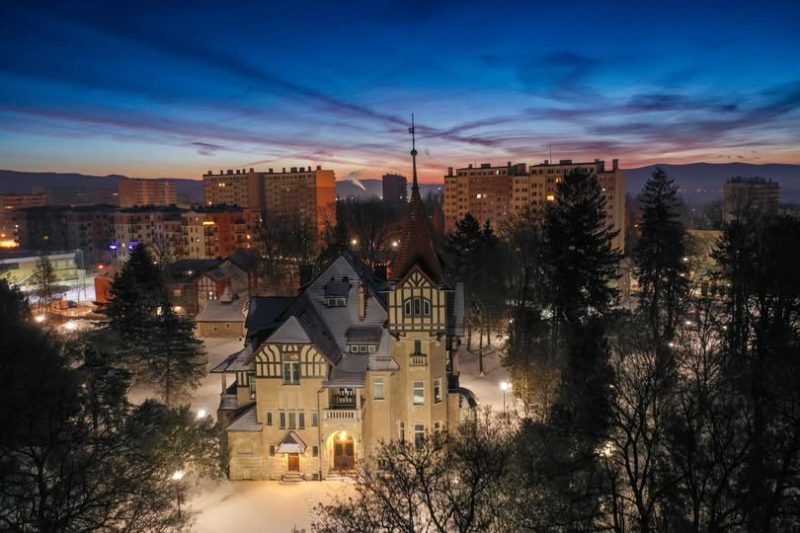 Zdjęcie nocne które przedstawia zabytkowy budynek przypominający zamek w centrum miasta