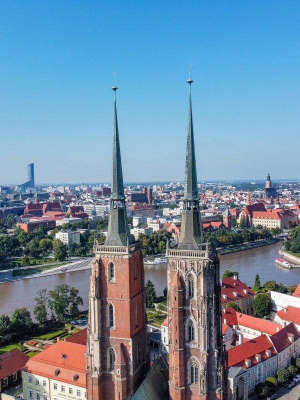 Zdjęcie z drona na wieże wrocławskiej katedry z miastem Wrocław widocznym w tle