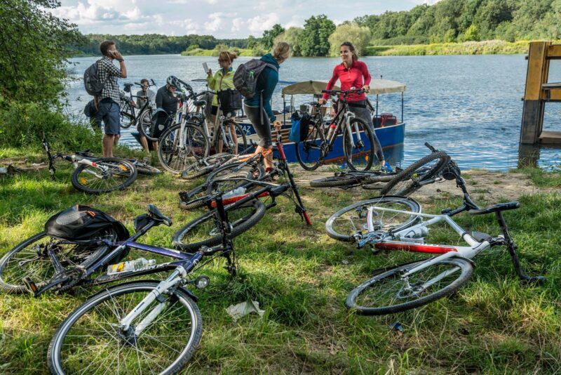 Zdjęcie grupy rowerzystów odpoczywającym przy brzegu rzeki