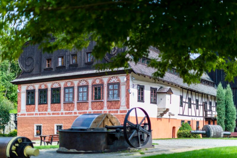 Zdjęcie budynku młyna papierniczego z widocznymi dużymi żeliwnymi maszynami przed wejściem