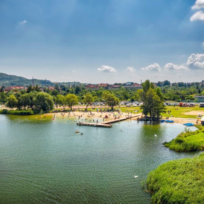 widok z góry na plaże z pomostem, otoczoną niskiej wysokości lasem