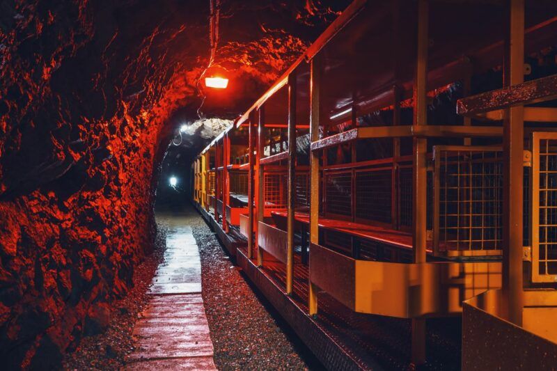 Widok na oświetlony korytarz z metalowym wagonikiem podziemnej kolejki
