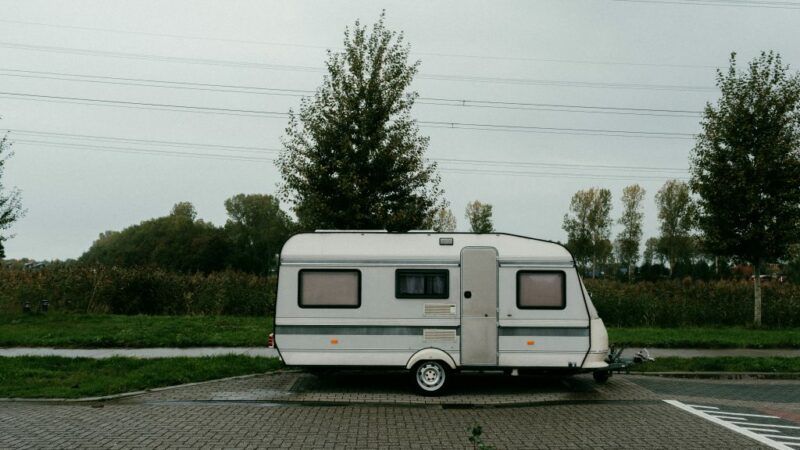 Przyczepa kempingowa stojąca parkingu na tle zachmurzonego nieba