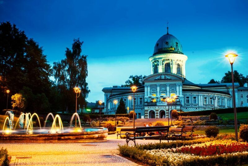 Wieczorny widok na zabytkowy budynek uzdrowiska z fontanną na pierwszym planie