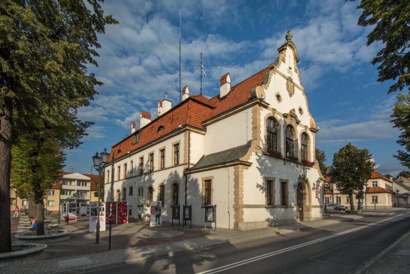 Historyczny budynek, z odnowioną elewacją w kolorze białym, poprzecinanym gzymsami z piaskowca.