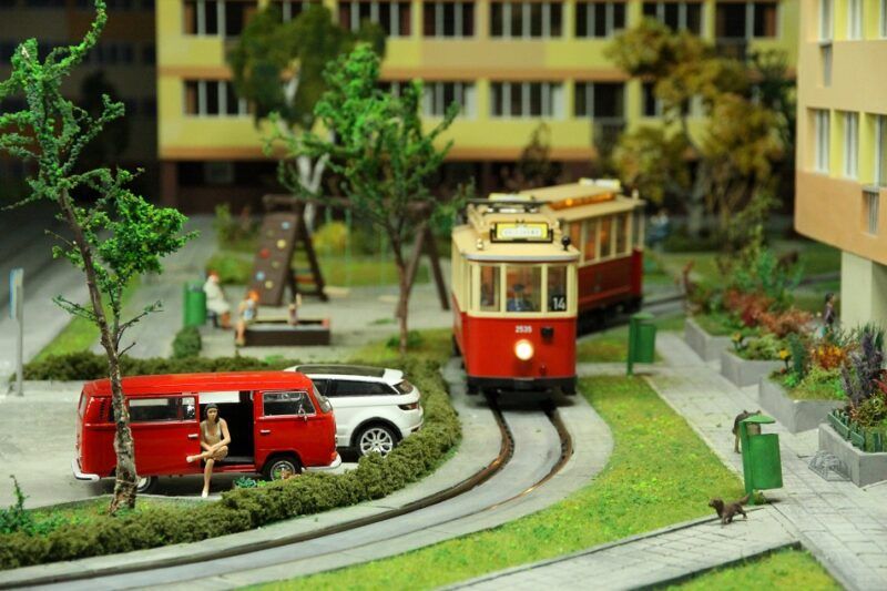 Makieta miasta z czerwonym tramwajem jadącym ulicą między żółtymi blokami