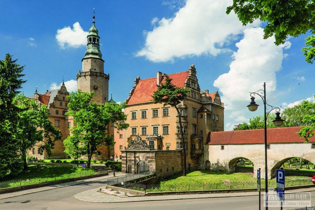 Zdjęcie renesansowego zamku z widocznym zadaszonym przejściem do bazyliki i pokaźną wieżą