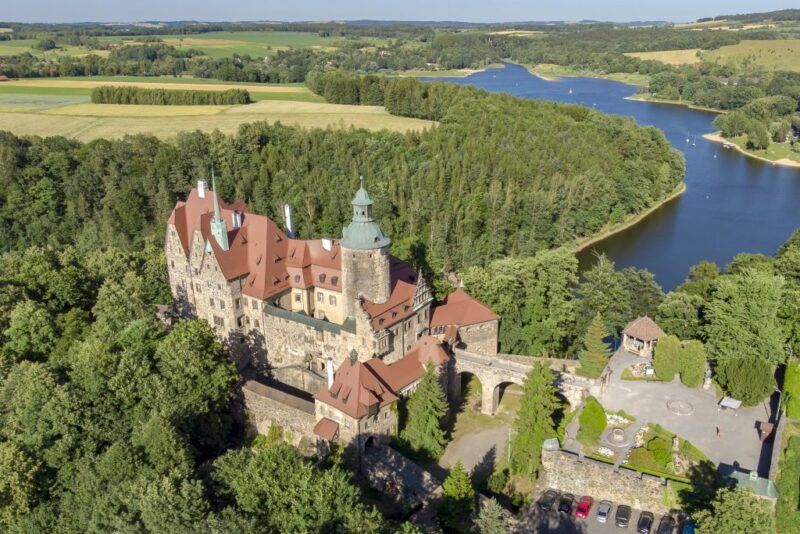 Widok z lotu ptaka na duży zamek z widocznym zbiornikiem wodnym w tle