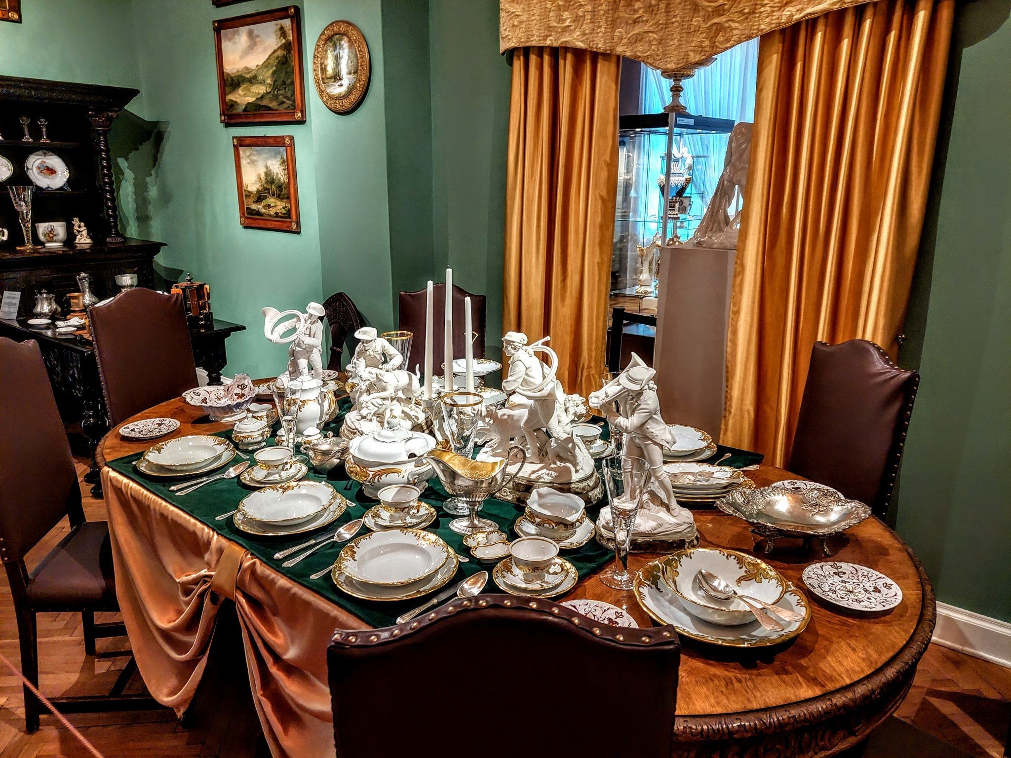 Dawna zastawa porcelanowa na stole z zielonym obrusem 