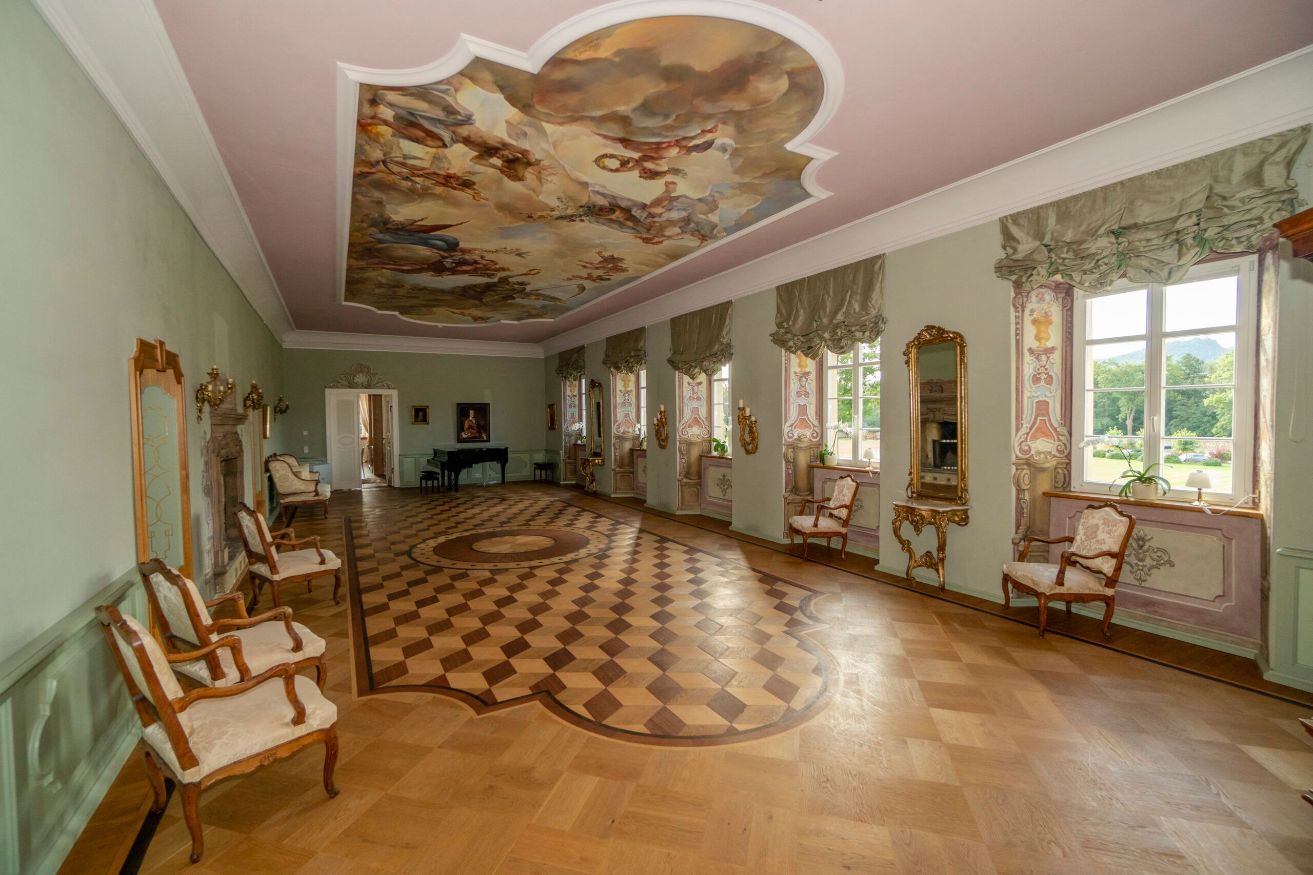 Stylowe, historyczne wnętrze komnat pałacowych, w których głównym dominantem są bogato zdobione wnęki okienne, sufit oraz drewniany parkiet.
