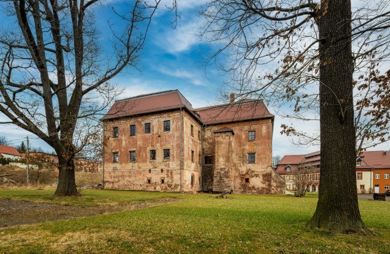 Na zdjęciu widać elegancki Pałac Struga – jasny, kilkupiętrowy budynek z ozdobnymi oknami i wieżyczką, otoczony zielenią i starymi drzewami, emanujący spokojem i historycznym urokiem.
