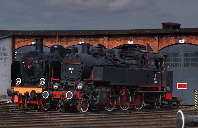 Zdjęcie czarnej, zabytkowej lokomotywy stojącej na torach przed halą muzeum kolejnictwa w Jaworzynie Śląskiej