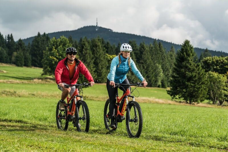 Dwójka rowerzystów jedzie po polnej ścieżce na tle góry