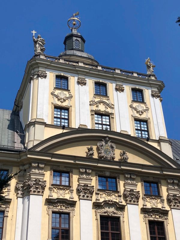 Widok z poziomu ulicy na szczyt barokowej, około 60-metrowej wieży z niezadaszonym tarasem widokowym z alegoriami 4 pierwszy fakultetów uniwersytetu na balustradzie.