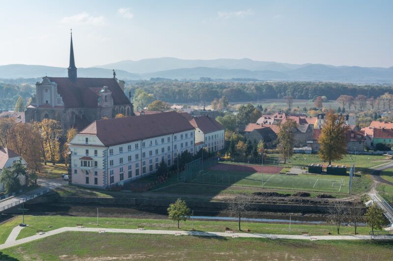 Widokz lotu ptaka na zabudowania miasteczka z widocznym zabytkowym kościołem po lewej stronie kadru