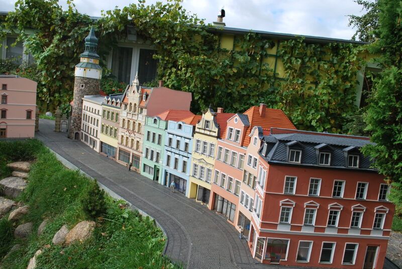 Miniatury kolorowych kamienic. Ich rząd kończy kamienna okrągła wieża.