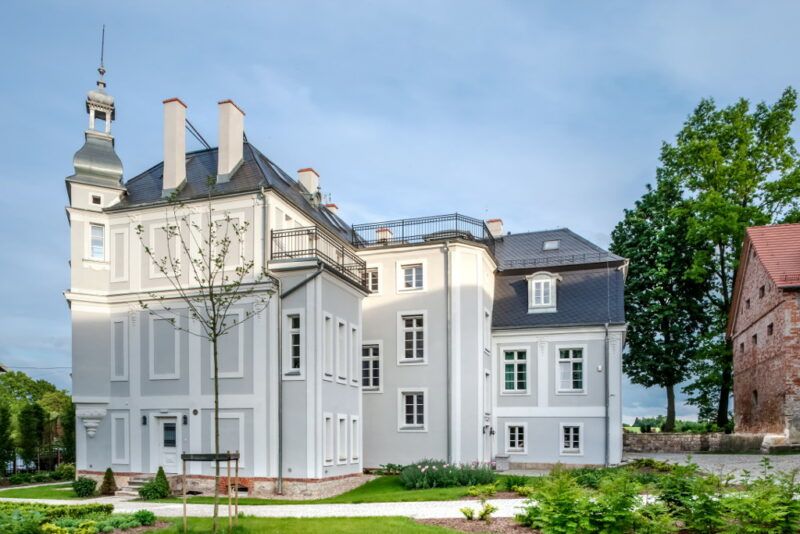 Biało-szary zabytkowy pałacyk, niedawno odnowiony- widok od drugiej strony