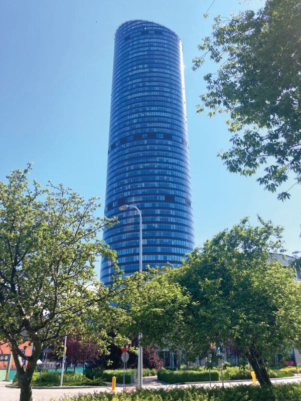Widok z poziomu ulicy na przeszklony wieżowiec Sky Tower przy słonecznej, letniej pogodzie