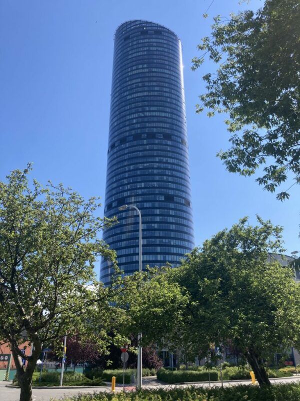 Widok z poziomu ulicy na przeszklony wieżowiec Sky Tower przy słonecznej, letniej pogodzie