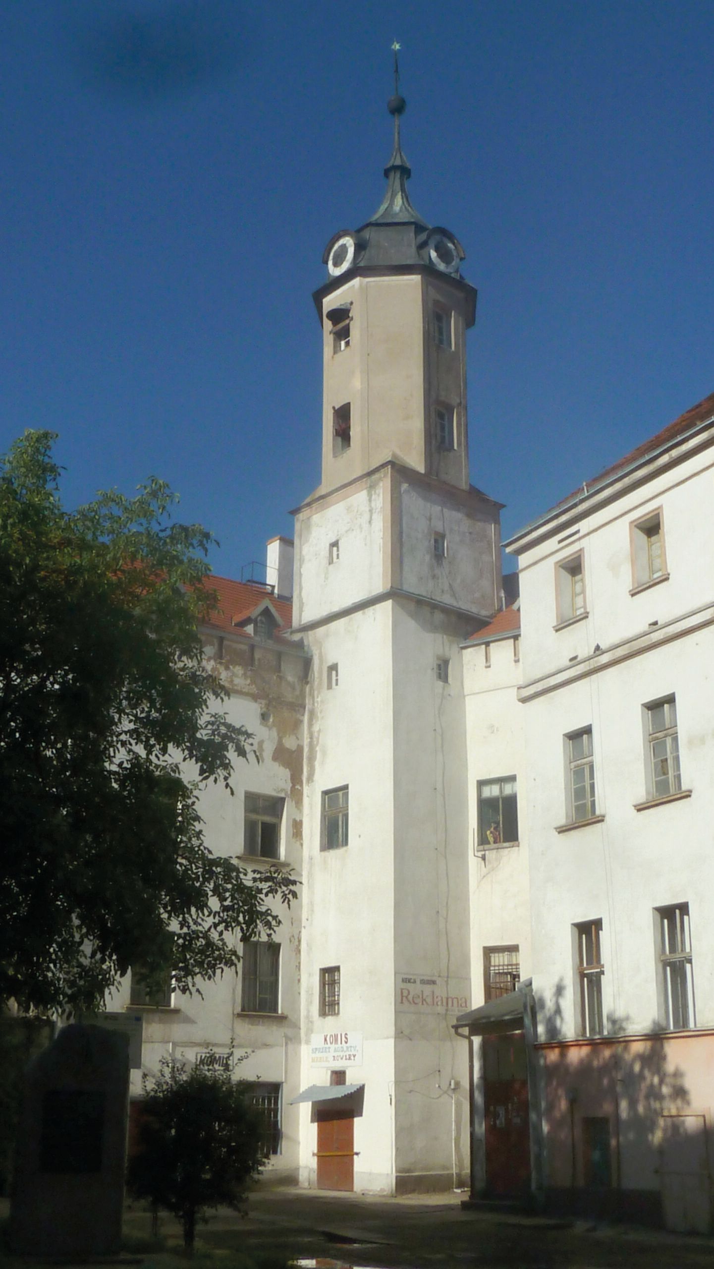 Widok na murowaną, pomalowaną na biało, zabytkową wieżę zamkową na tle błękitnego nieba