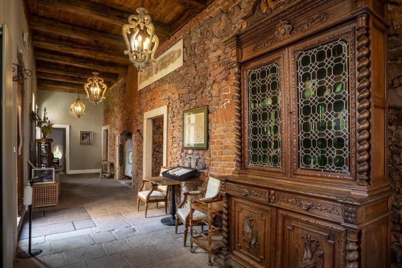 Wnętrza z zabytkowymi drewnianymi elementami wyposażenia. Na pierwszym planie imponujący kredens.