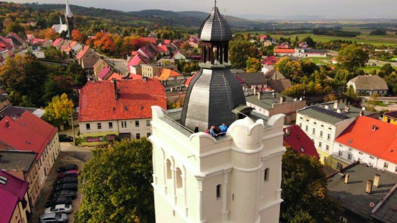 Widok z poziomu szczytu białej wieży widokowej w Złotym Stoku z okolic złotostockiego rynku. Widoczna panorama Sudetów i okolic Złotego Stoku.