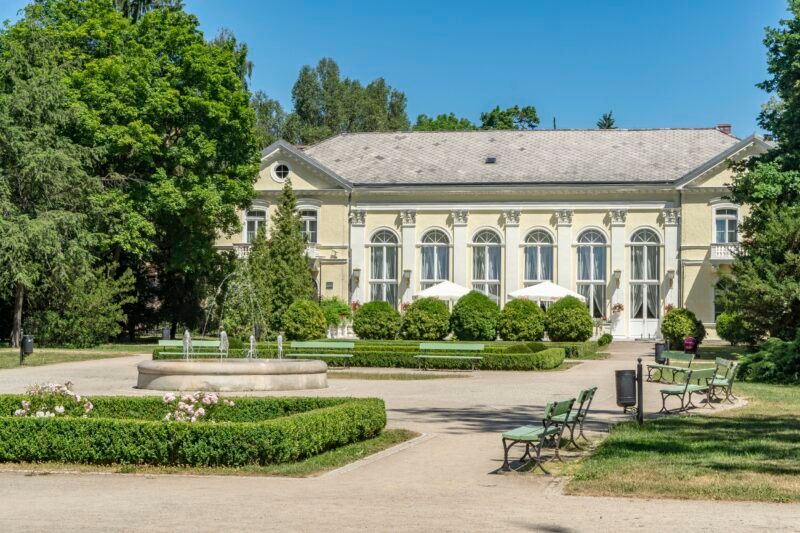 Widok na Park Zdrojowy, budynek z jasną elewacją i zadbanym ogrodem.