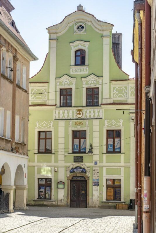 Budynek z biało-zieloną elewacją, w tle niebieskie niebo.