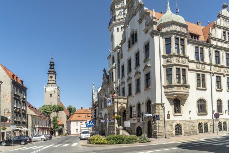 Widok na budynki i ulicę w mieście,  w tle niebieskie niebo.