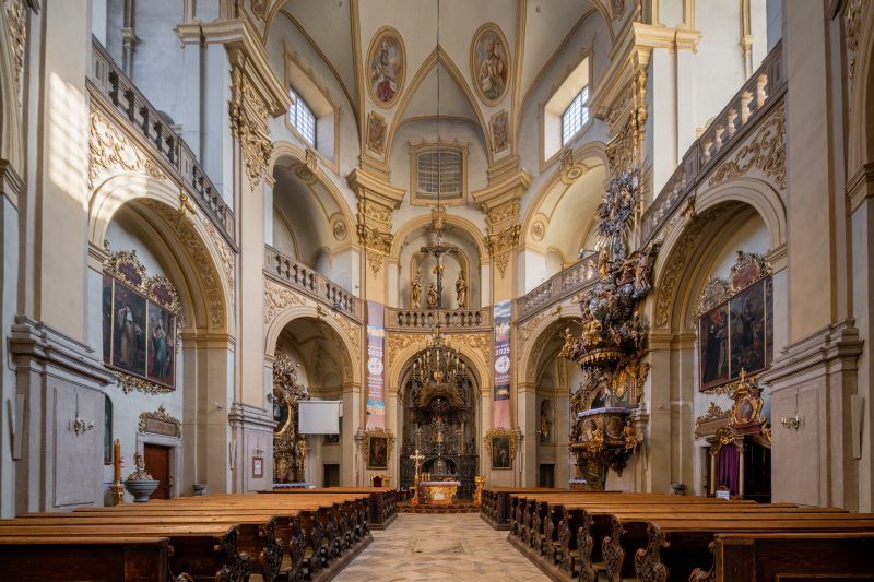 Na zdjęciu widać bogato zdobione wnętrze sanktuarium w Wambierzycach z ołtarzem pełnym złoconych detali, rzeźb i obrazów otoczonych ciepłym światłem świec.