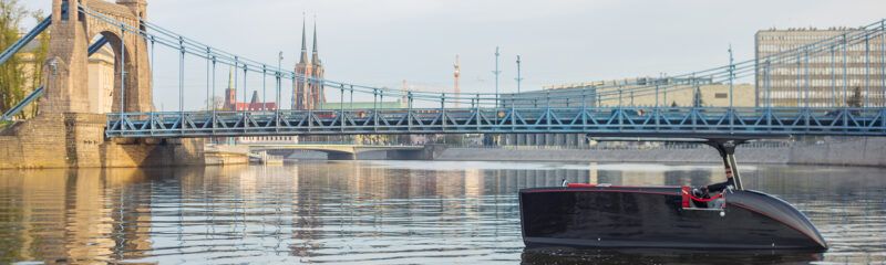 Most o konstrukcji stalowej wiszący przez rzekę posiadający nitowane elementy w kolorze pastelowobłękitnym