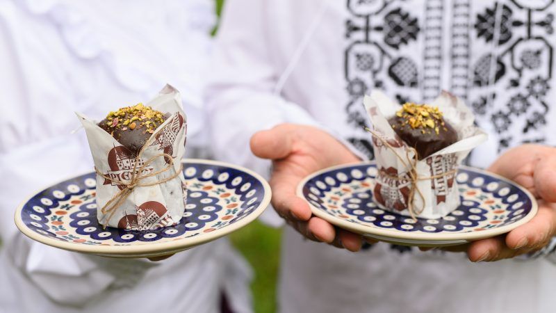 Kobieta i mężczyzna w śląskich strojach ludowych prezentują deser Bomba Legnicka