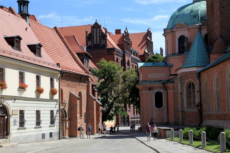 Wąskie przejście wyłożone kostką brukową między katedrą a buydynkiem ceglanym