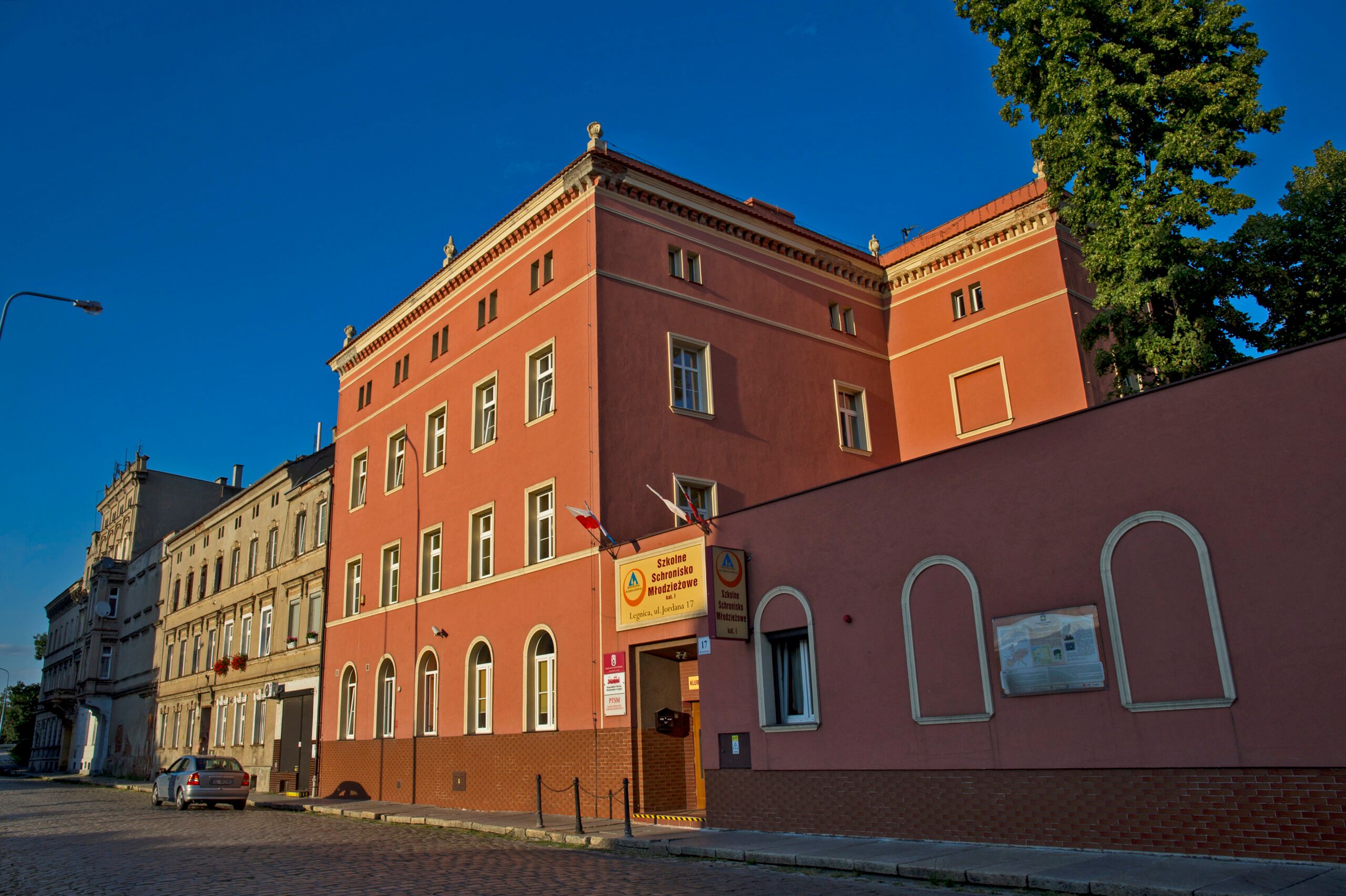 Trójkondygnacyjny, prostokątny budynek połączony z jednopiętrową oficyną.