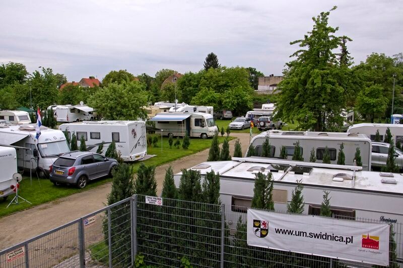 Widok na plac campingowy z zaparkowanymi samochodami kamperowymi. 