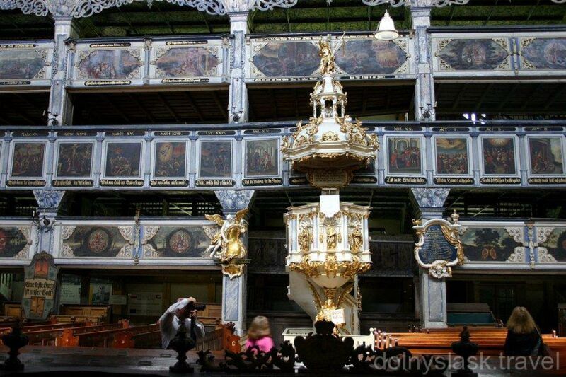 Wnętrze drewnianego kościoła z 3 piętrami oraz złoto dekorowaną amboną